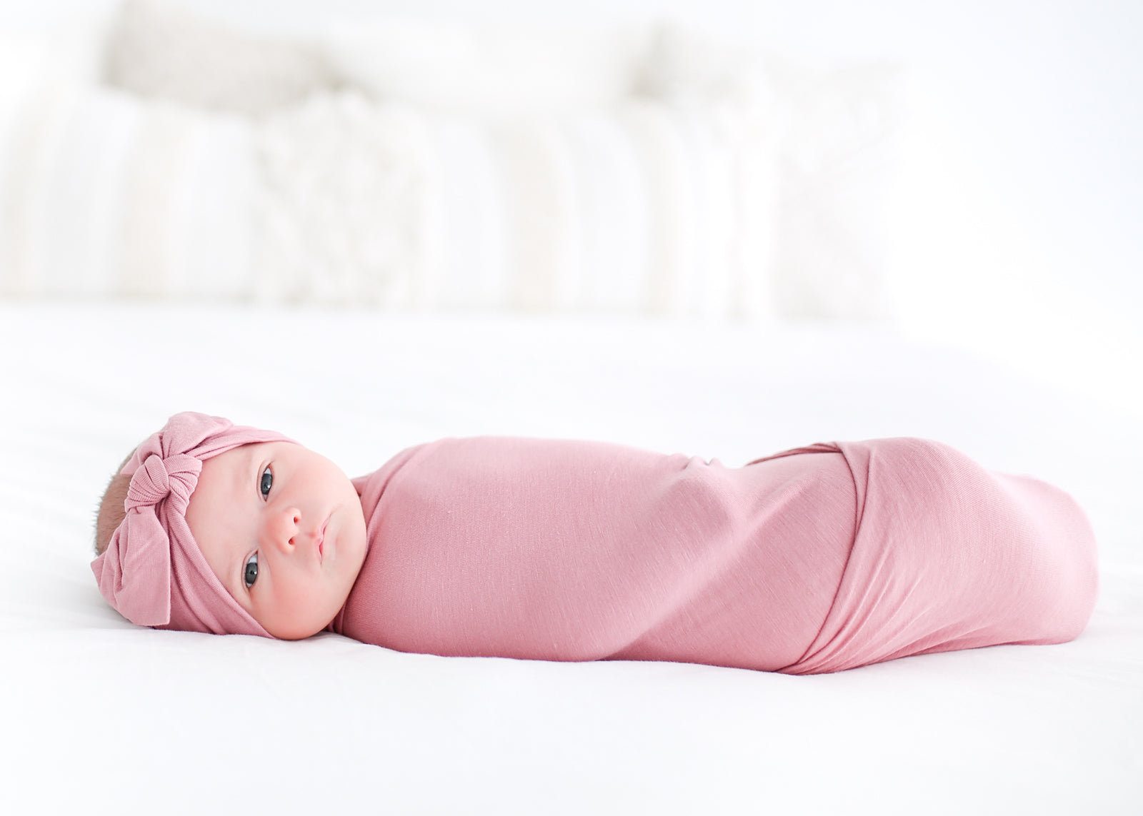 Swaddled Newborn Girl in Pink Swaddle Looking at Camera