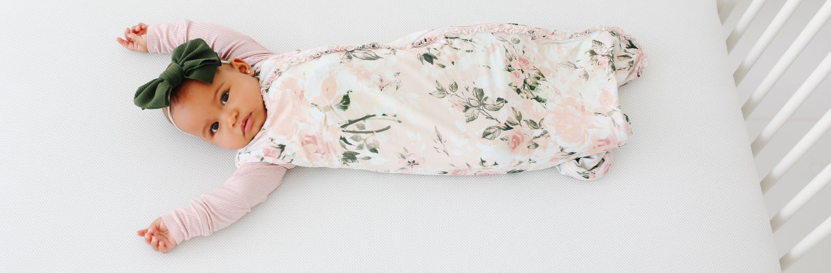 baby wearing floral infant sleeping bag in crib