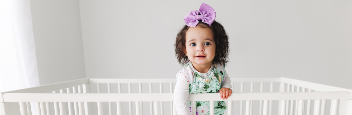 baby girl standing in floral baby sleeping bag