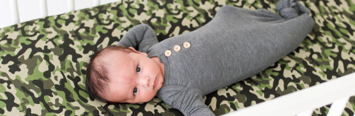 baby laying on camo print crib sheet cover 