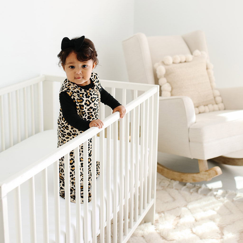 baby in crib wearing leopard print sleep sack