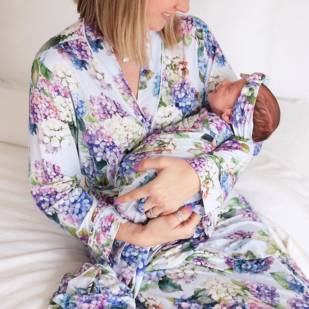 mother sitting on bed holding infant wearing matching floral prints