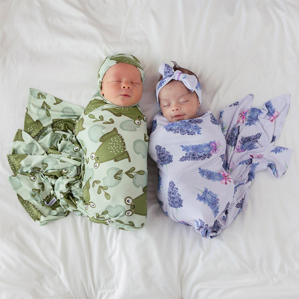 two newborn babies wrapped in frog and floral print sheets