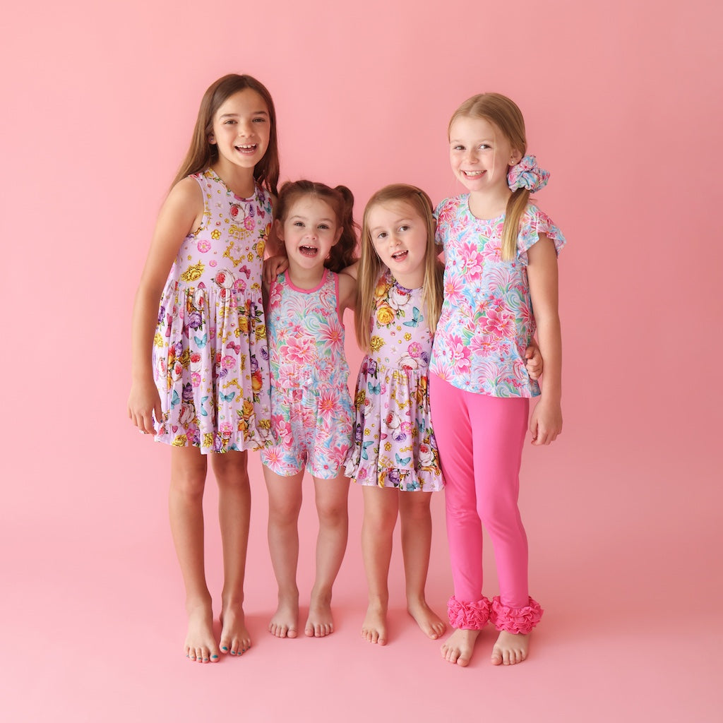 Four girls standing together wearing matching bright floral prints