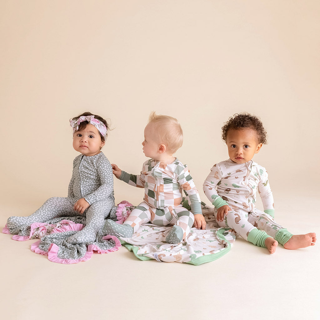 three infants sitting on blankets wearing onesies