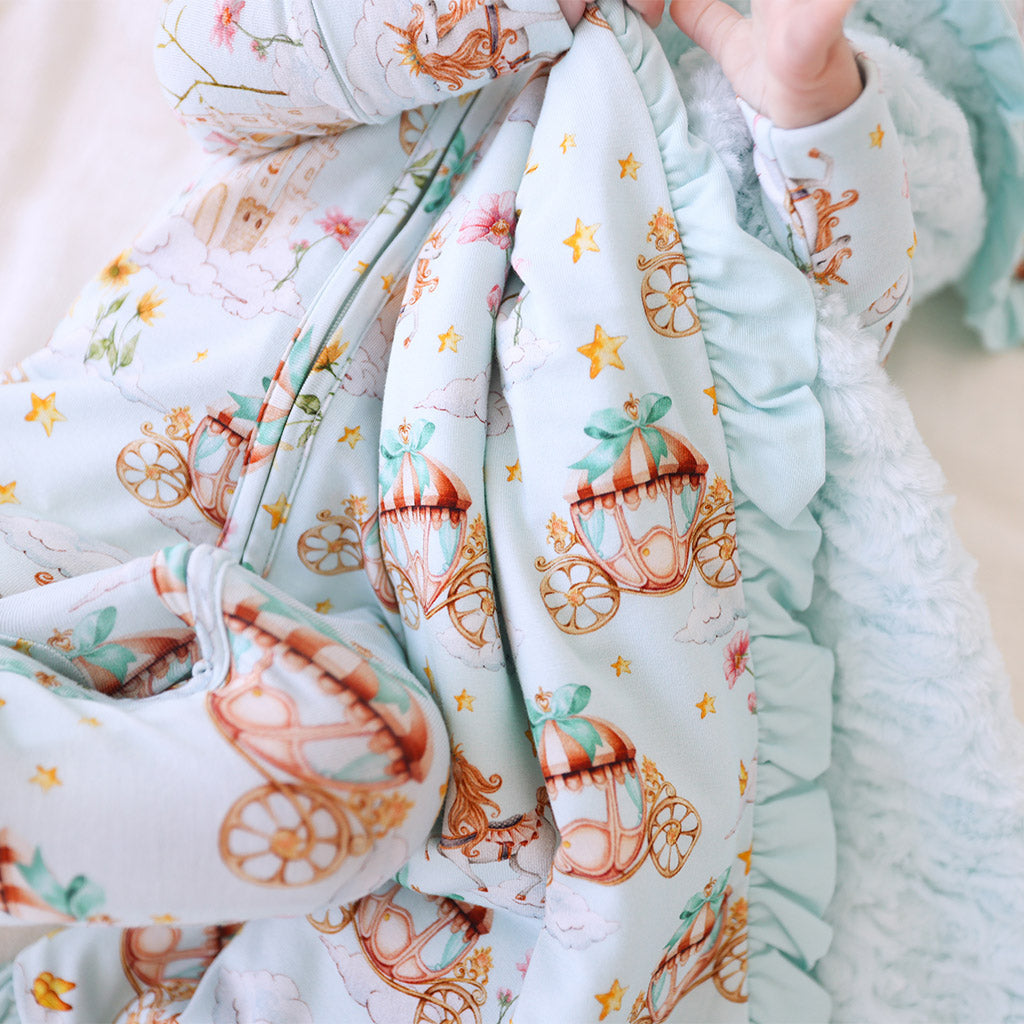 baby lying down wearing onesie holding matching print blanket