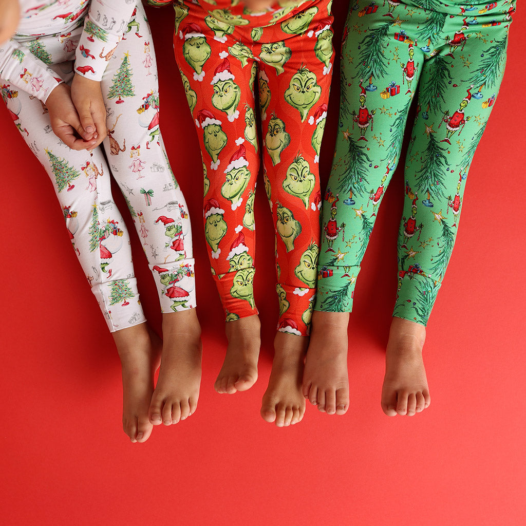 three childrens' legs wearing various Dr. Seuss' The Grinch themed prints pajamas