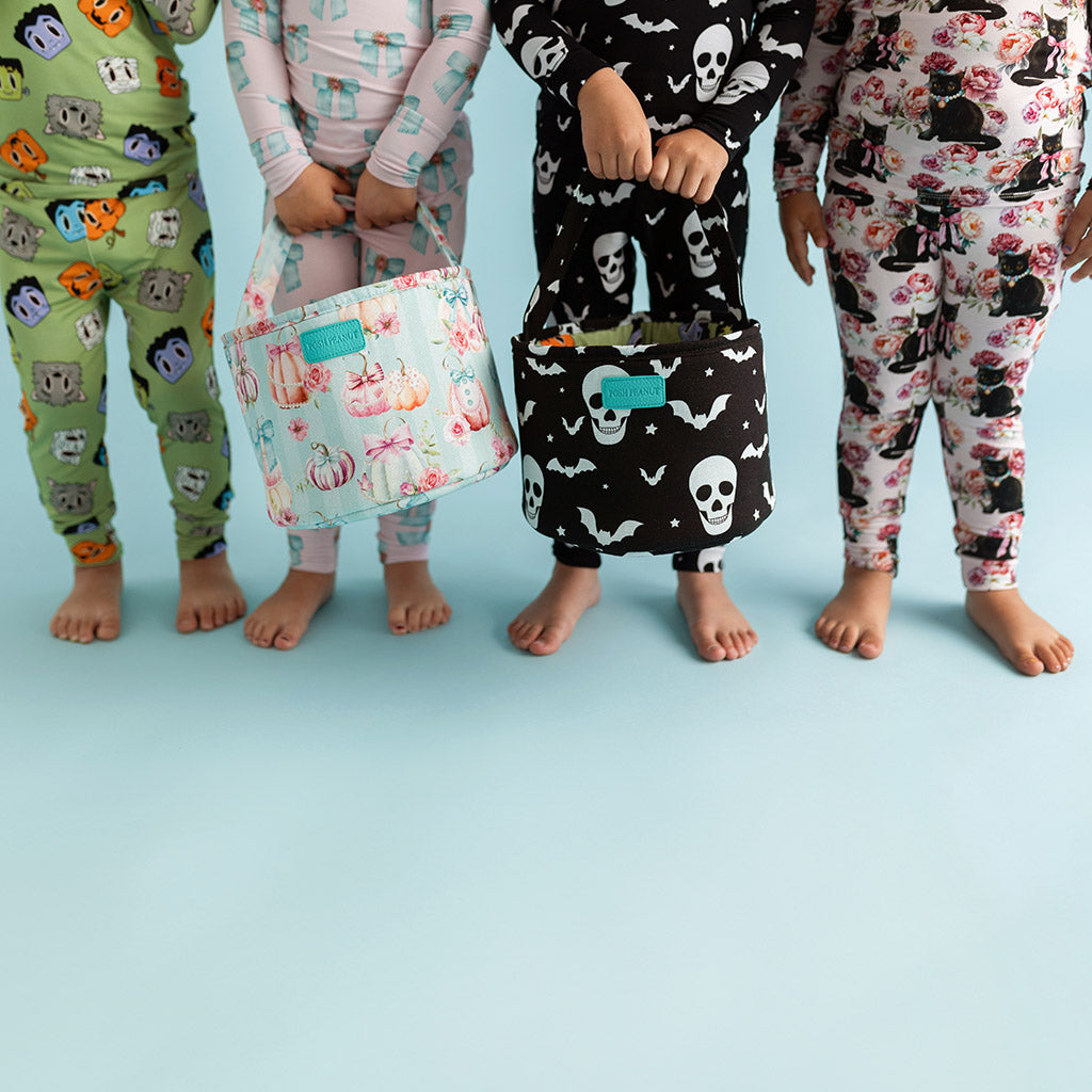 four kids wearing different halloween themed pajamas, two holding matching baskets