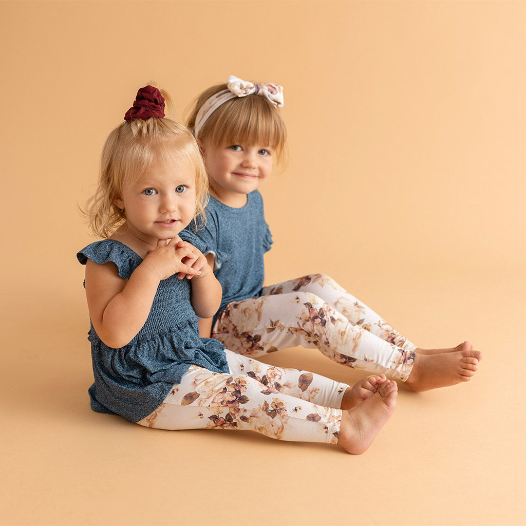 two girls sitting side by side wearing matching outfits