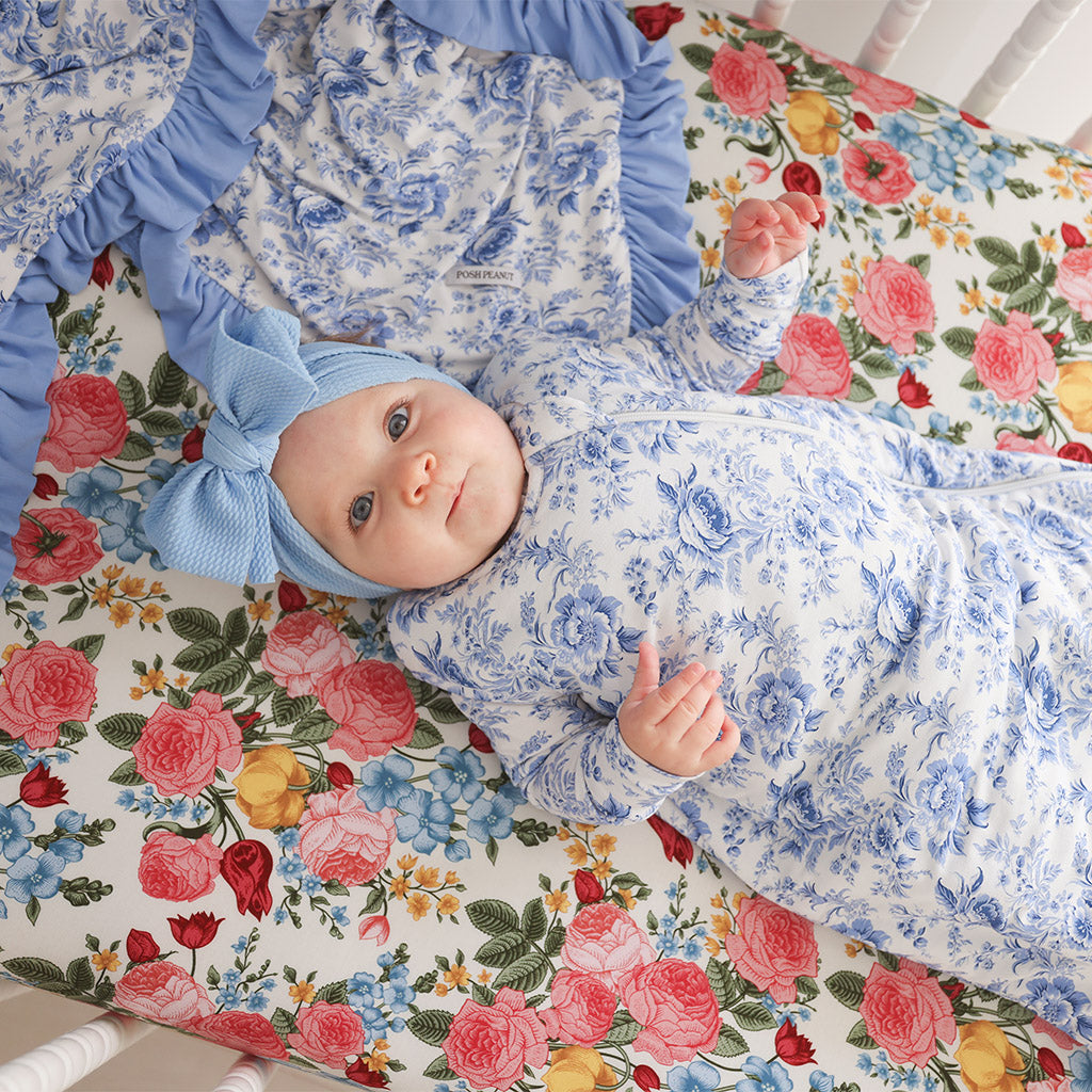 baby lying in crib wearing blue and white floral print onesie