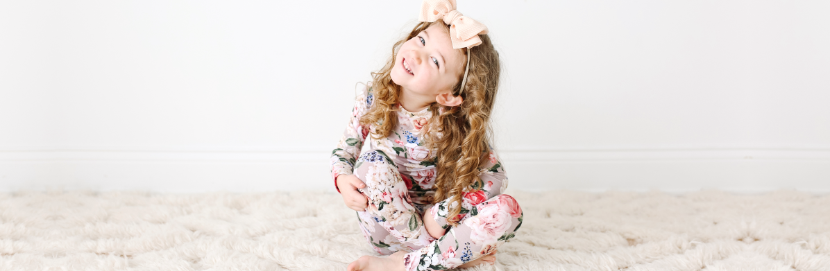 girl sitting on floor in floral toddler pajamas