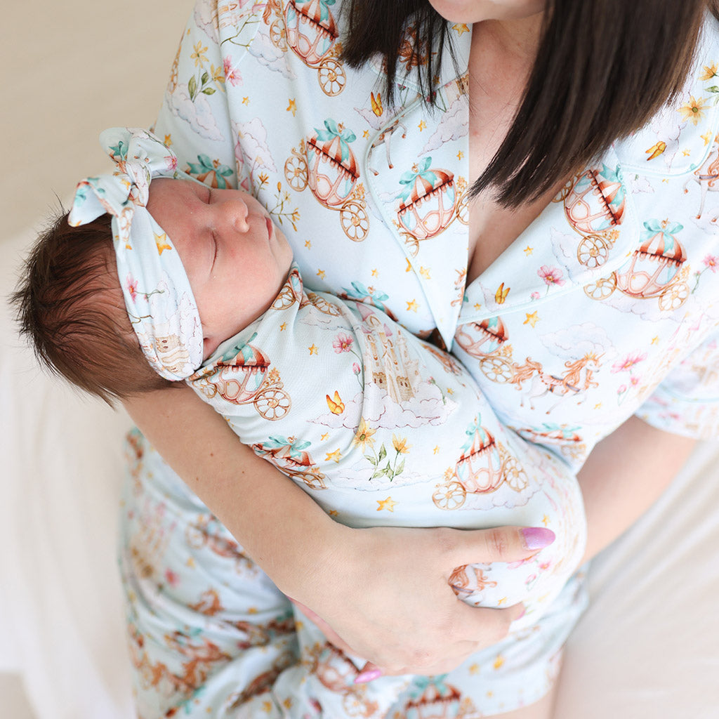 Mother holding newborn wearing matching fantasical print outfits