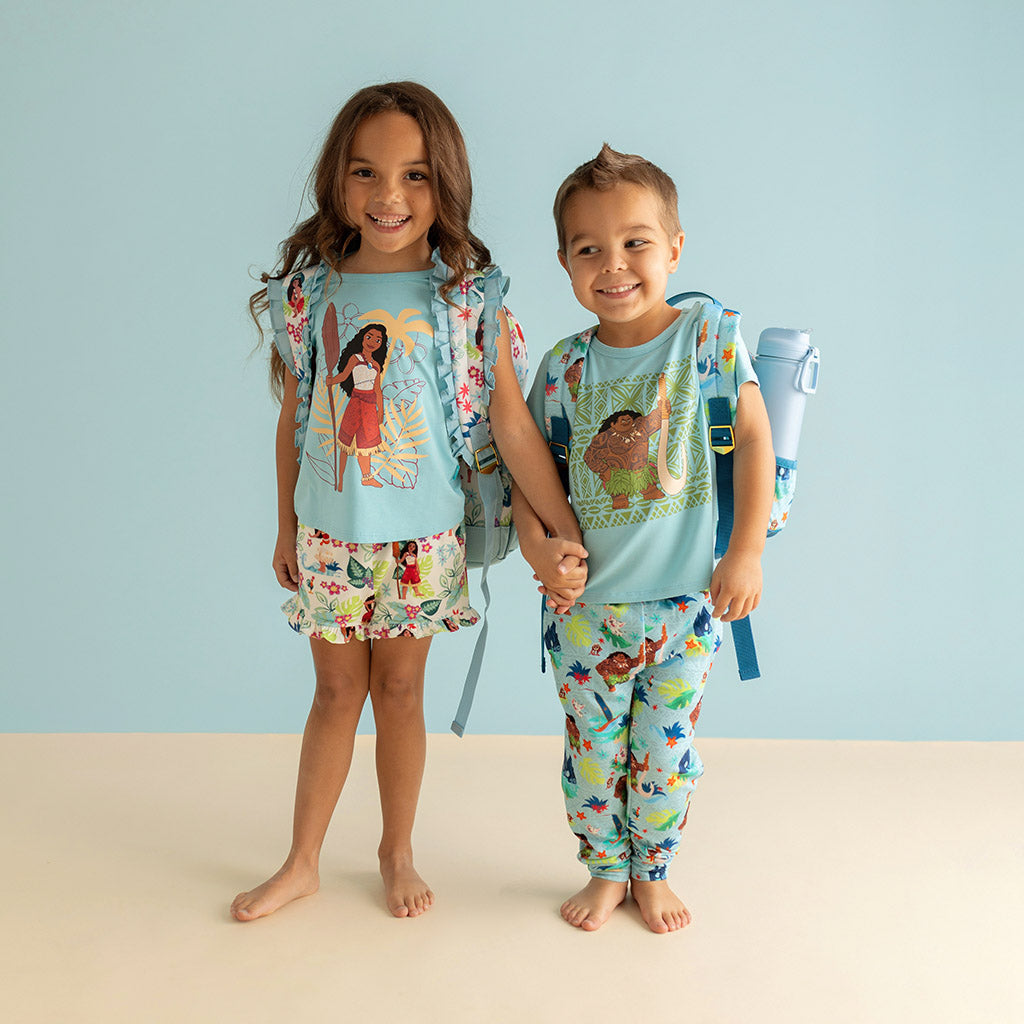 boy and girl siblings holding hands wearing matching outfits and backpacks