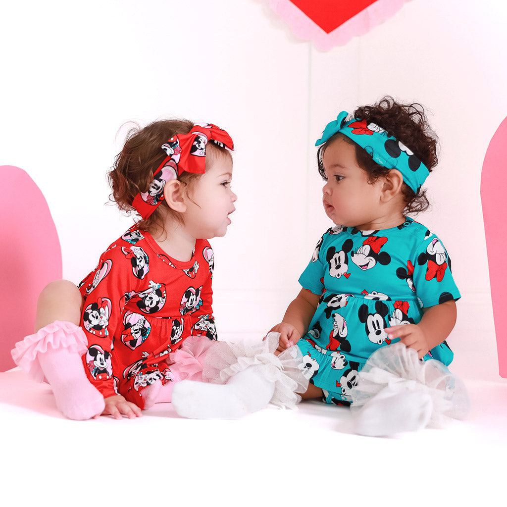 two infants wearing matching disney dresses