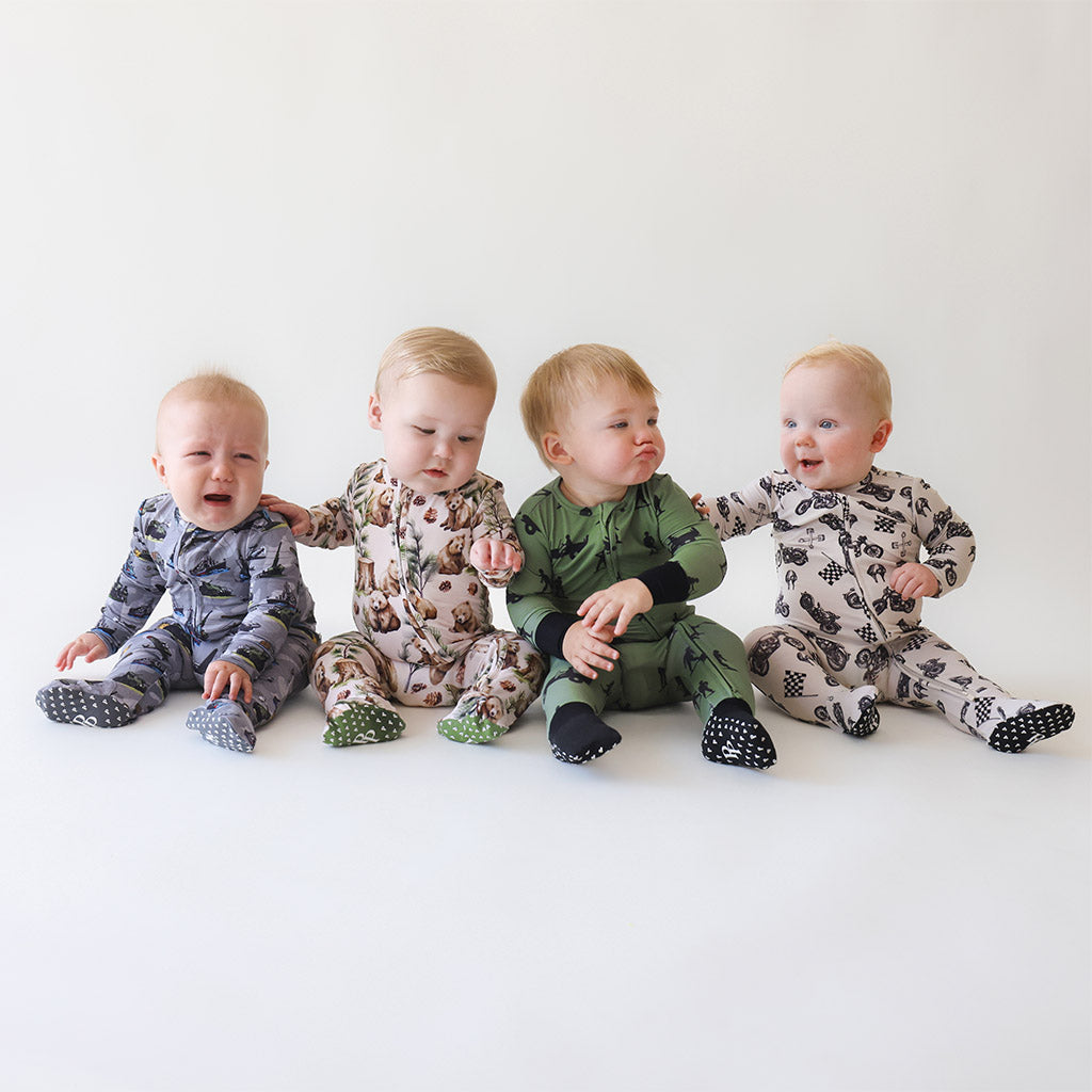 four infant boys sitting together wearing one-piece bodysuits