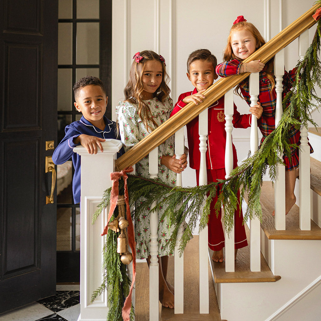 four children posing on staircase wearing various holiday themed pajamas