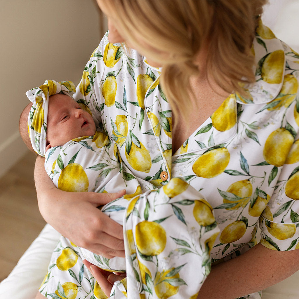 Mother holding infant wearing matching lemon print outfits