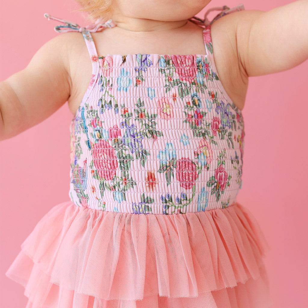 close up of baby wearing floral print pink smocked tulle bodysuit dress