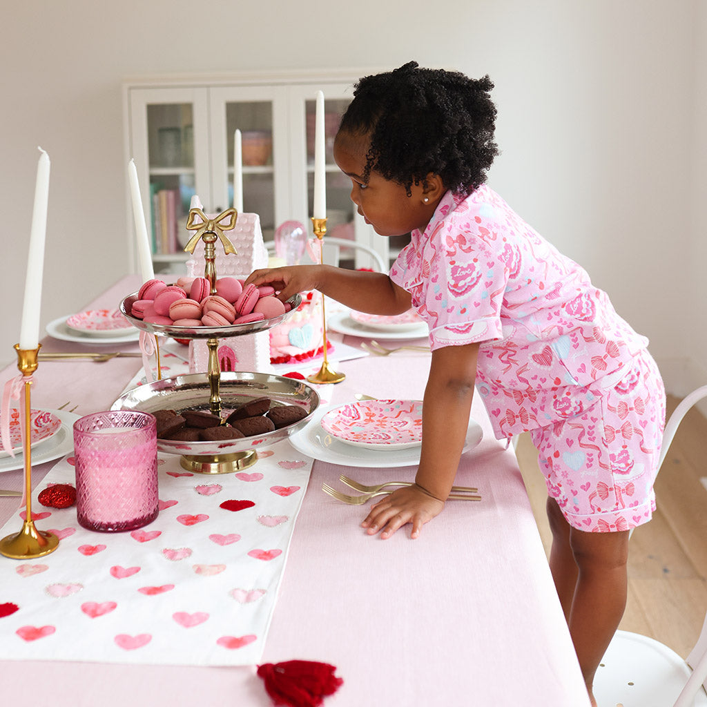 toddler standing on chair taking pink macaron 