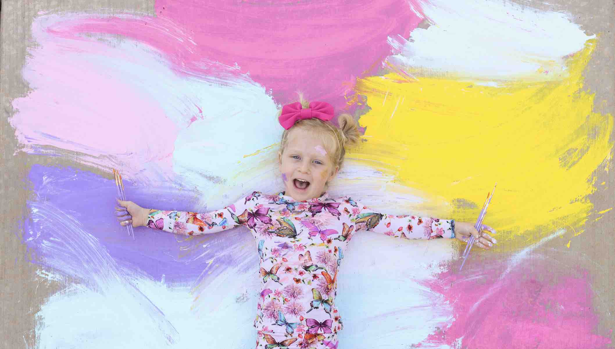 girl laying on rainbow paint  