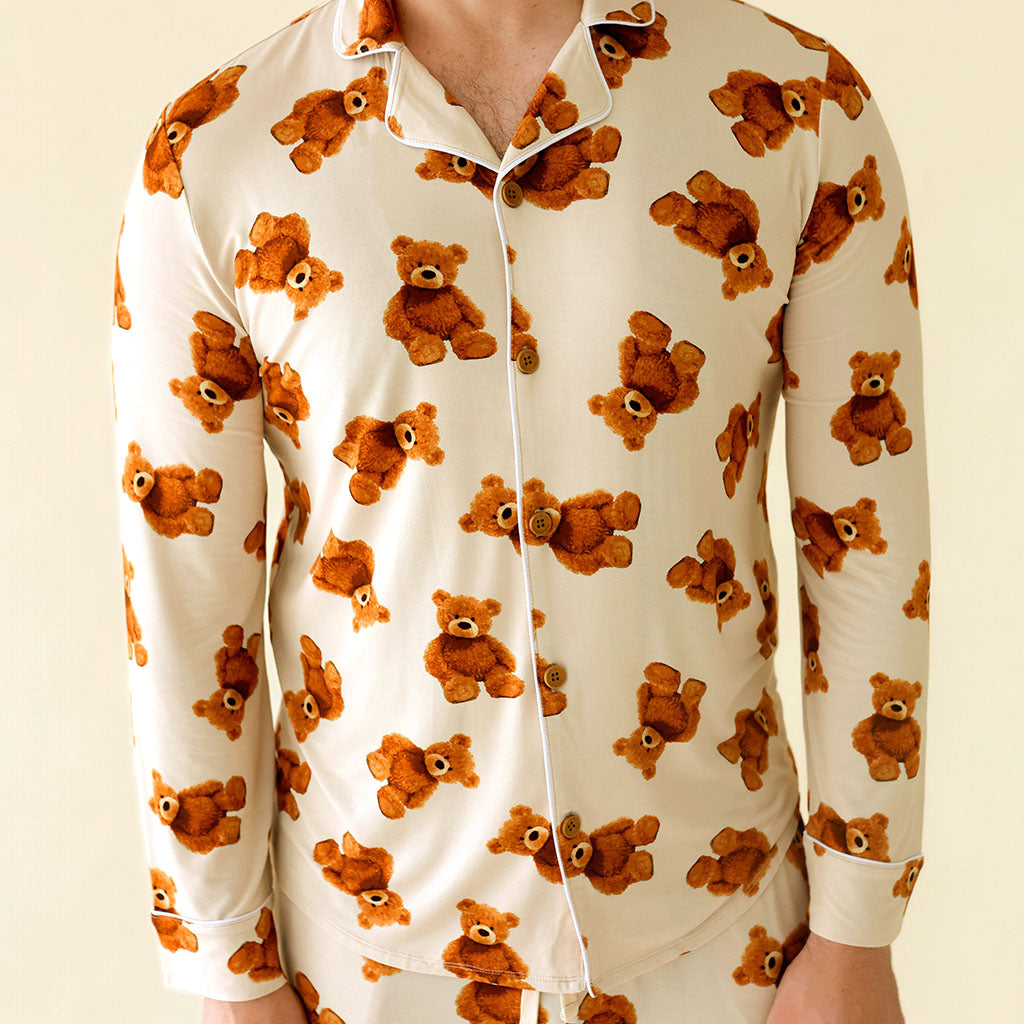 White shirt with brown teddy bear pattern worn by a person on a beige background