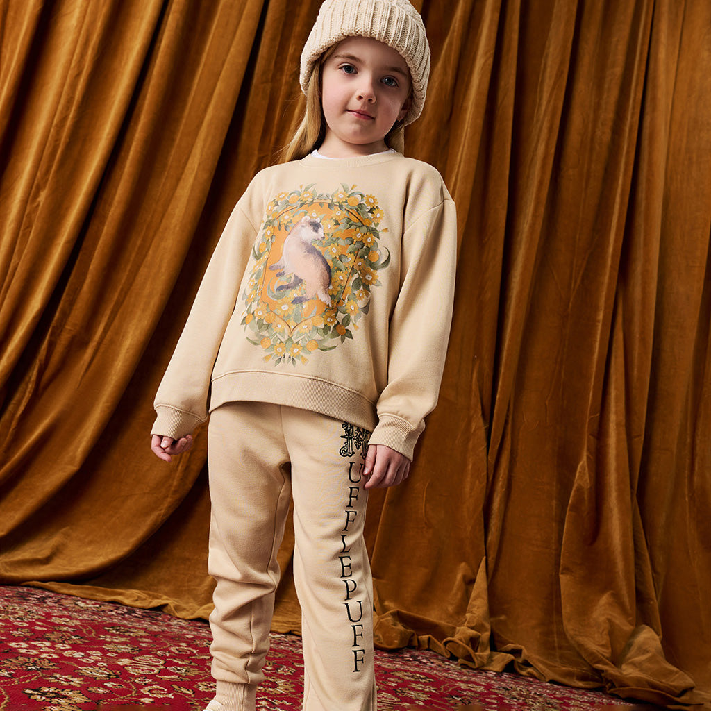 Child wearing tan Harry Potter Hufflepuff printed sweatshirt and jogger set.