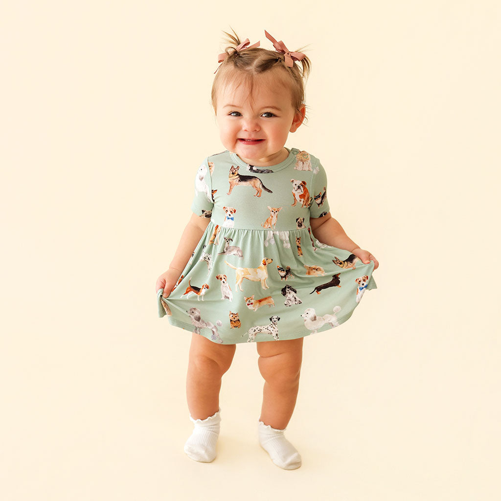 Child wearing a dress with dog pattern on a beige background