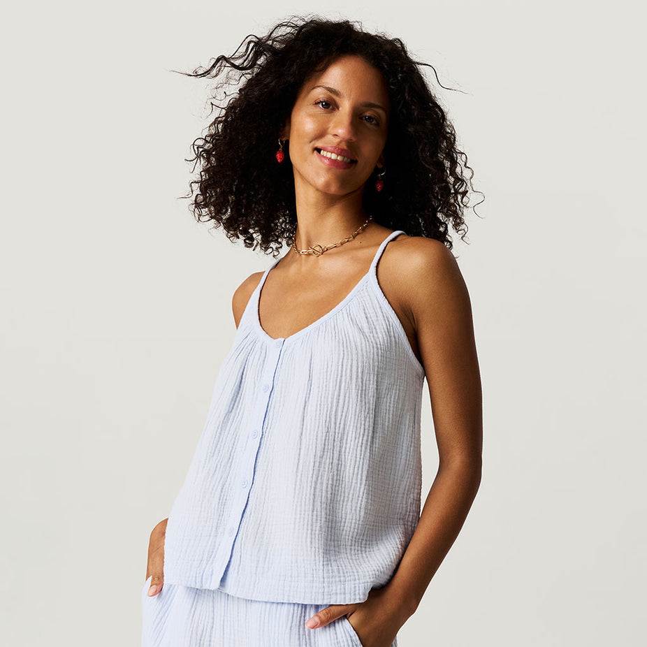 Woman wearing a light blue sleeveless top and pants against a plain background