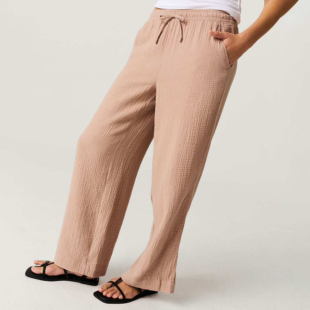 Brown cotton crinkle pants worn by a person on a white background