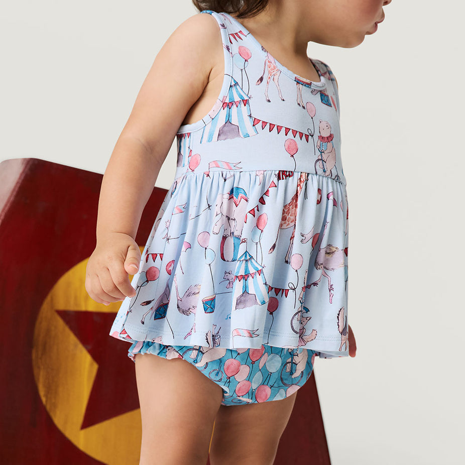 Child wearing a light blue sleeveless top and shorts with colorful patterns on a plain background