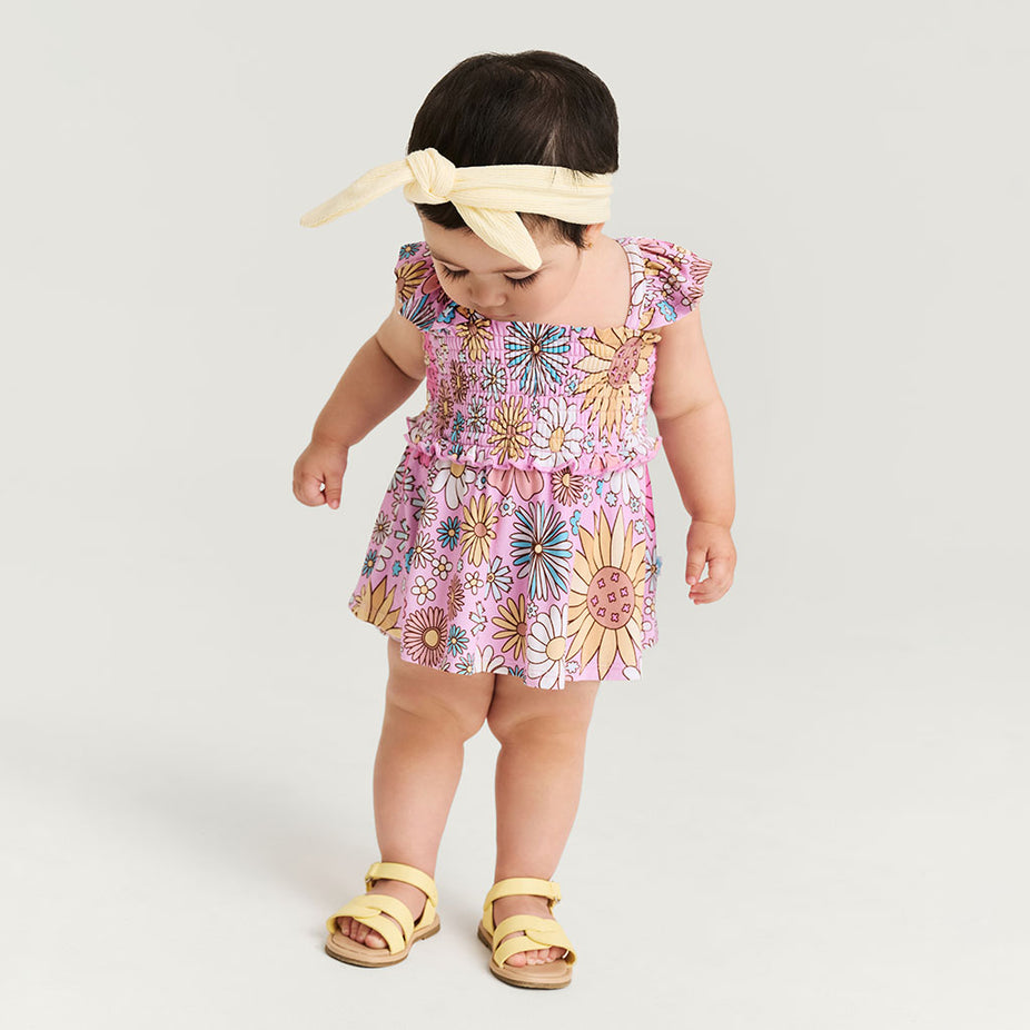 Child wearing a floral dress with a plain background