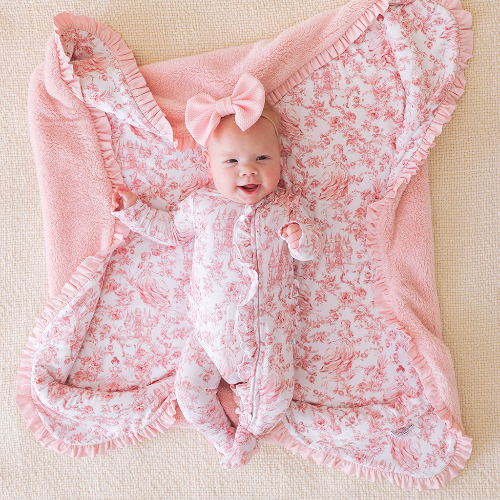 Baby wrapped in a pink floral blanket with a bow on a beige background