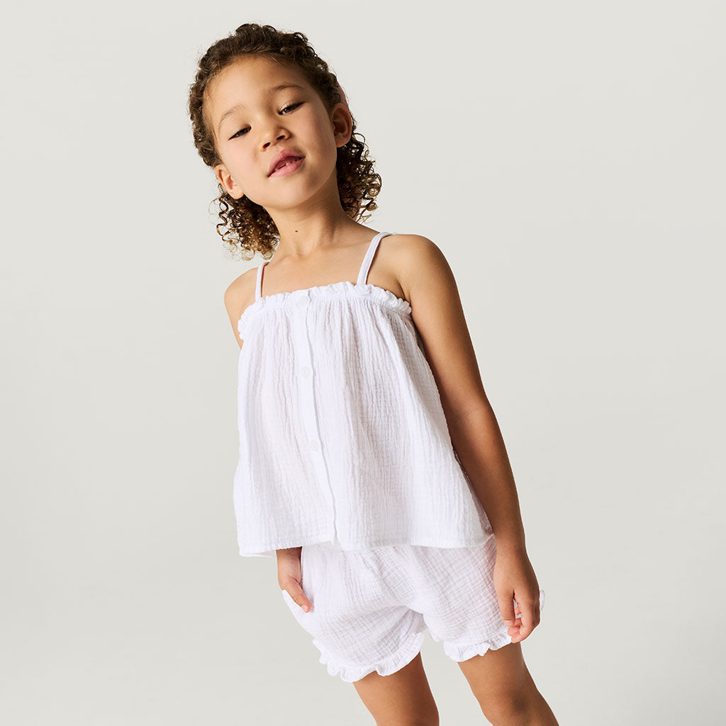 Child wearing a white cotton crinkle short set against a plain background