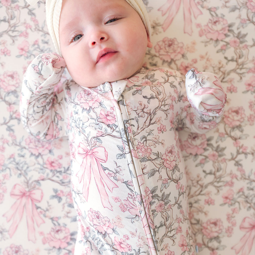 Baby in a floral outfit lying on a floral blanket