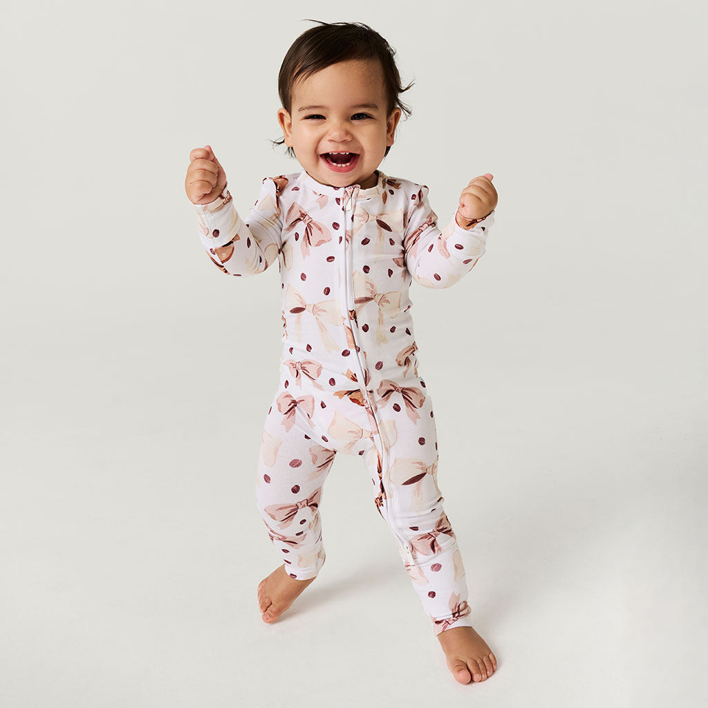 Child wearing a coffee beans and bows one piece on a plain background.