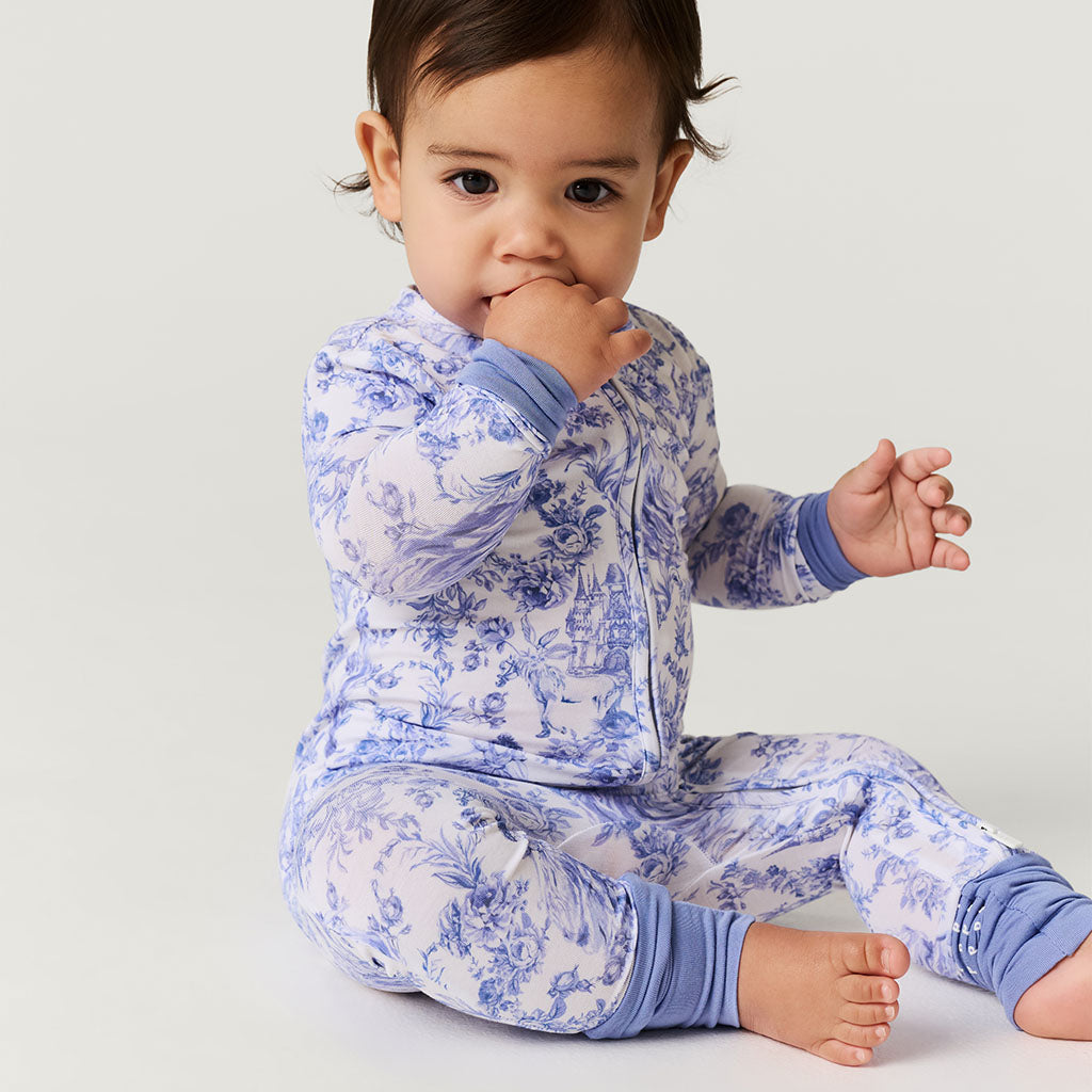 Baby wearing blue floral one piece on a light gray background