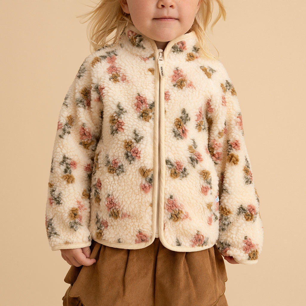 Close-up of a girl wearing the Amber print sherpa zippered jacket, on a cream background
