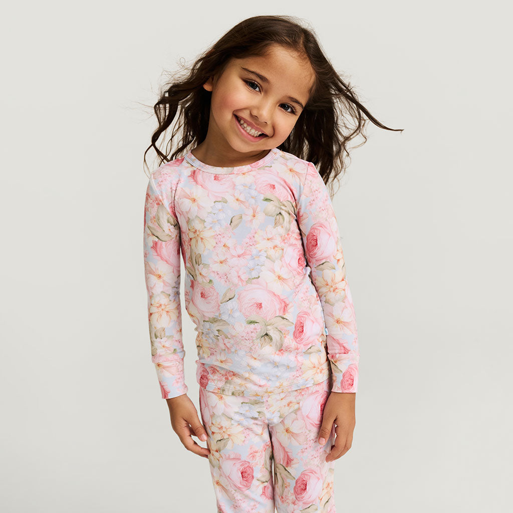 Young girl wearing a floral pajama set on a plain background