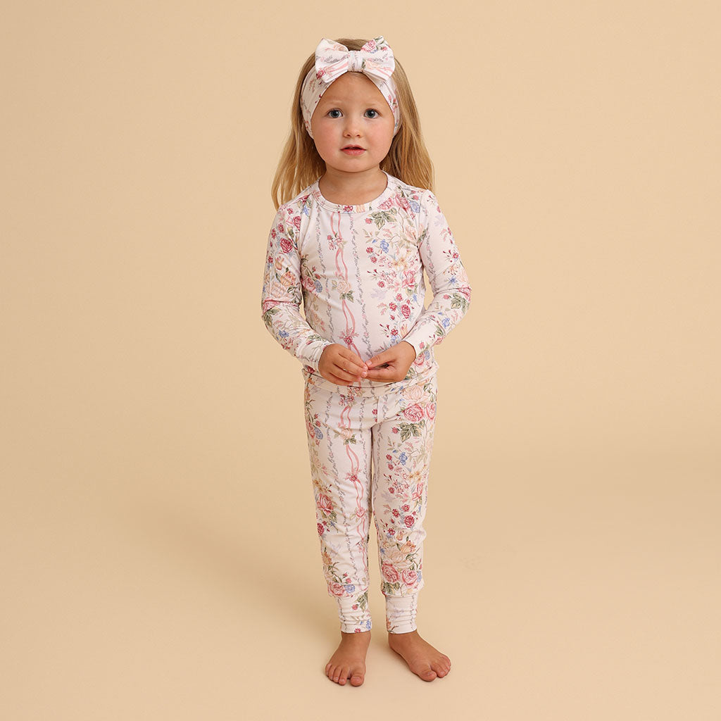 Girl standing wearing the Janey print classic pajama set with a headband, on a cream background