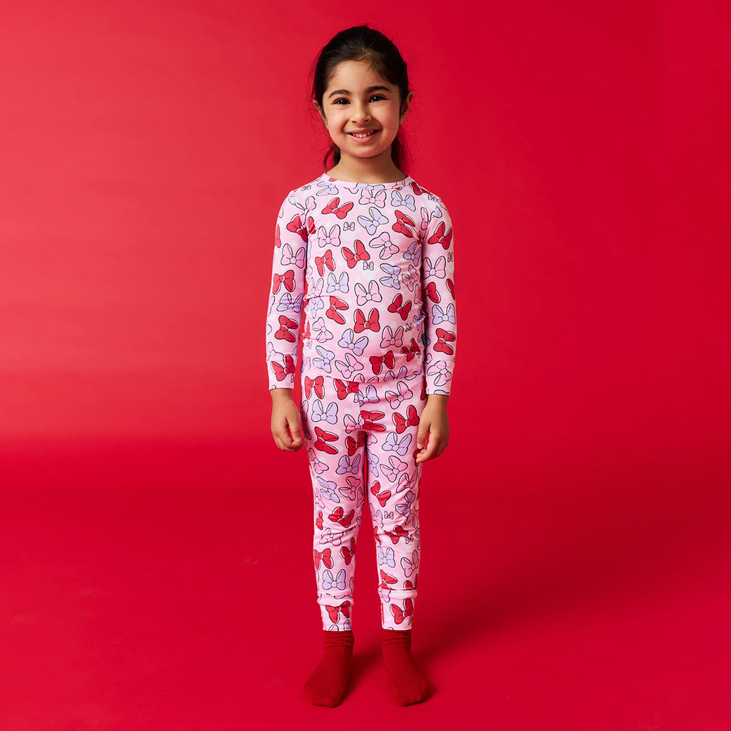Child wearing a Disney bow patterned long sleeved pajama set