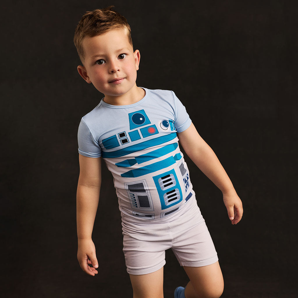 Child wearing a Star Wars-themed outfit with R2-D2 design on a dark background