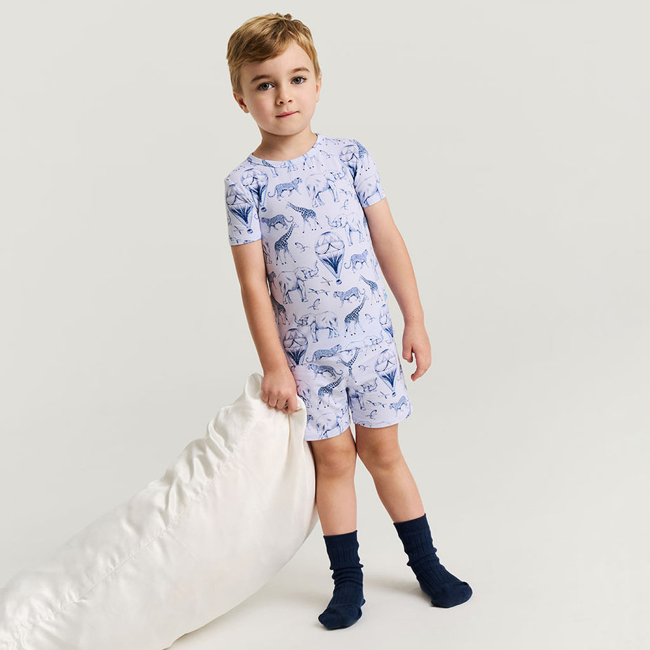 Child wearing a animal-patterned pajama set on a plain background