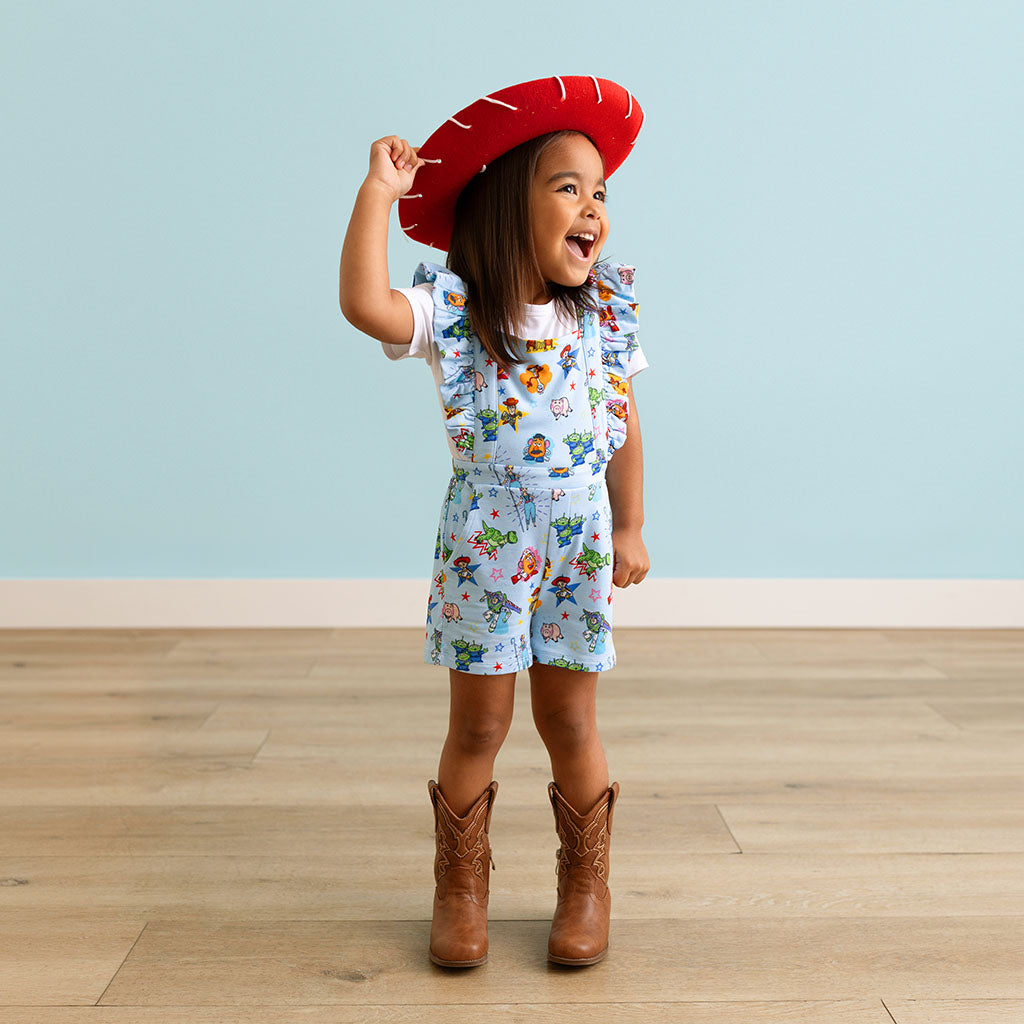 Child wearing a red beret, patterned outfit, and brown boots on a light blue background