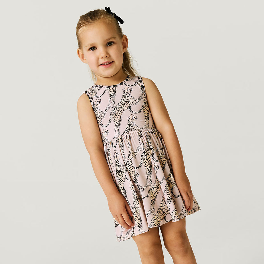 Young girl wearing a patterned dress on a plain background