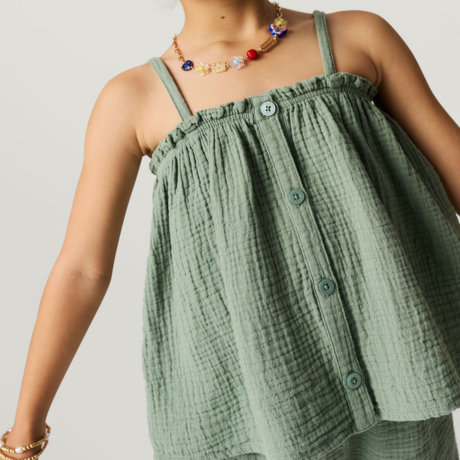 Green textured top worn by a person on a plain background