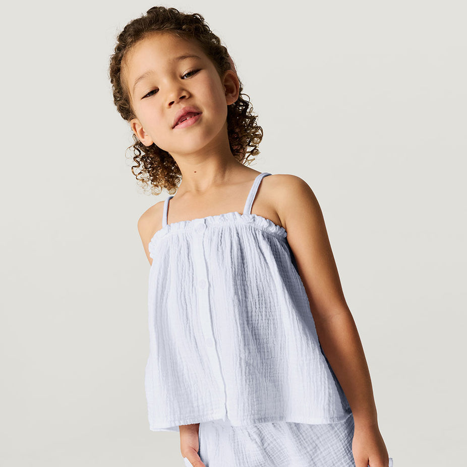 Young girl wearing a light blue top against a plain background