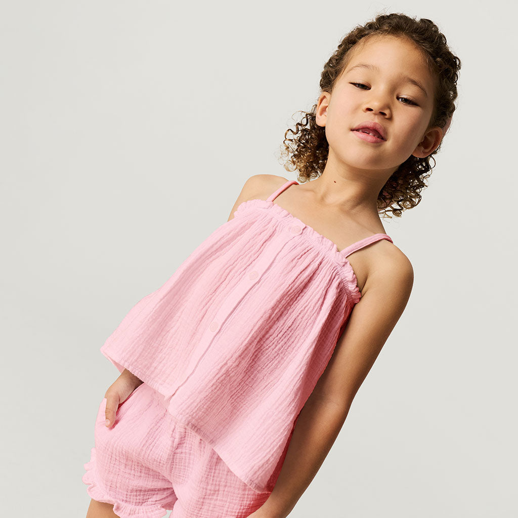 Child wearing a pink top against a plain background