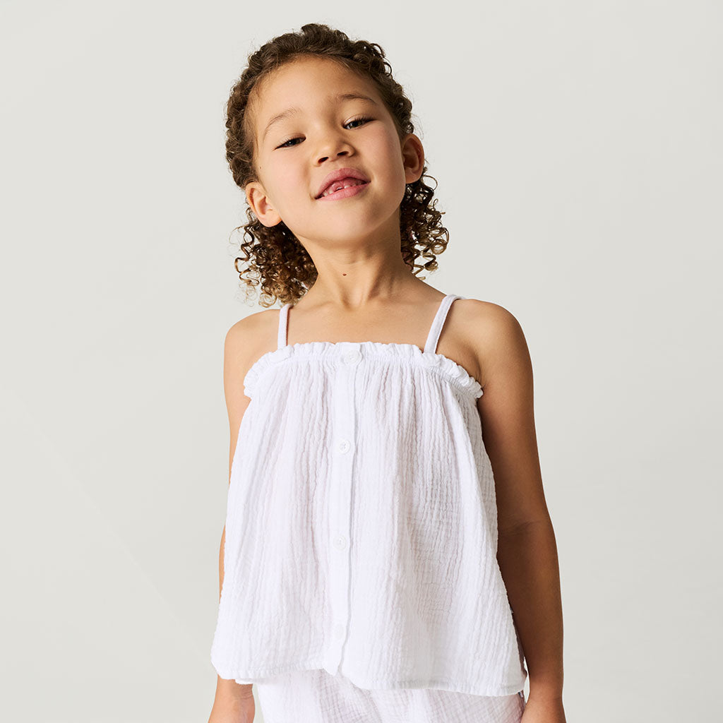 Child wearing a white top against a plain background